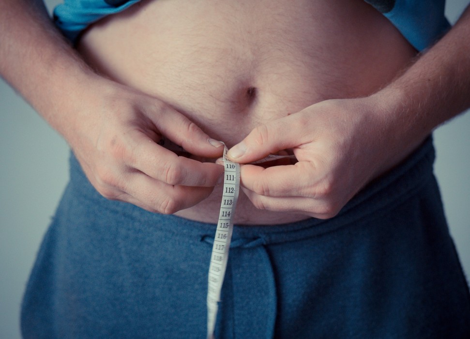 Bauch eines Mannes mit Maßband